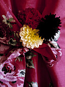 Single stem flowers and black feathers on pink floral fabric