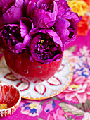 PInk peonies in red vase with floral tablecloth