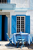 Blue folding chairs at table outside sunlit Greek villa