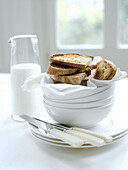 Fresh toast and milk with bowls and knives on table