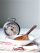 Metal alarm clock with wooden spoon in bowl