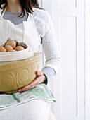 Woman holds mixing bowl and eggs in preparation for baking