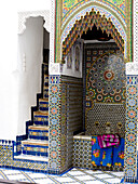 Stoffe in einem marokkanischen Innenhof mit geometrischen Fliesen und eingelassenem Wasserbecken Nordafrika