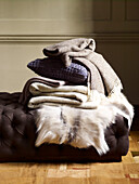 Folded woollen fabrics and fur rug on daybed