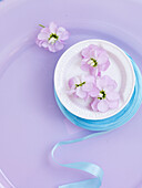 Lilac flowers and blue ribbon in bowl of water