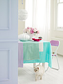 Cat walks in front of table with pastel fabrics in white interior