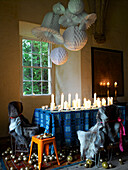 Display of lit candles on table below large paper ornaments in Scotland UK
