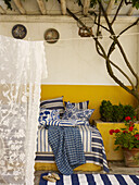 Blue and white fabrics with net curtain on veranda of Spanish home