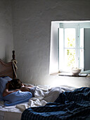 Woman sleeping at open window of Spanish villa