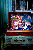 Vintage suitcase with assorted tableware outside rustic cabin