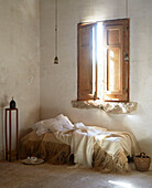 Unmade daybed below closed wooden shutters in Sicilian home