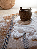 Basket and linen with woven floor mat in Sicilian home