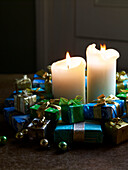 Lit candles with group of tiny presents and baubles