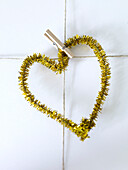 Gold tinsel heart displayed on clothes peg on string