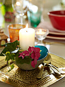 Lit candle with ivy and gold spoons