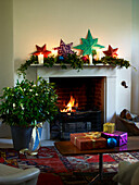 Star decorations and ivy with lit fire and presents