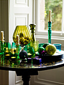 Sammlung von grünem Glasgeschirr und Kerzenständer auf antikem Beistelltisch