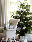 Chair stacked with presents and gifts under tree with white stars and flowers