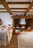 Bücherregal auf dem Kaminsims über dem beleuchteten Holzofen im Wohnzimmer des Hauses der Familie Cranbrook, Kent, England, UK