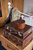 Brown leather suitcases on basket in bedroom of Cranbrook home, Kent, England, UK