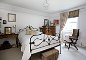 Metal worked bedframe and antique furniture in white bedroom of Tenterden home, Kent, England, UK