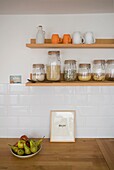 Storage jars and a bowl of pears with a single word 'enjoy', on wooden kitchen work surface in St Leonards home, East Sussex, England, UK