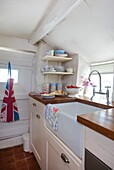 Union Jack apron hangs on back door in white washed cottage kitchen in Corfe Castle, Dorset, England, UK