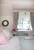 Koordinierte floral gemusterte Kissen und Vorhänge im Schlafzimmer des Cottage in Corfe Castle, Dorset, England, UK