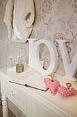 "Liebesherzen und ein aufgeschlagenes Buch mit dem Wort Liebe"" auf einer gemalten Konsole im Haus in Cranbrook, Kent, England, UK"""