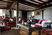 Brown leather sofa and metalworked coffee table in beamed living room in Sandhurst cottage, Kent, England, UK