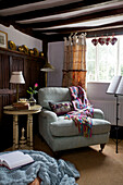 Sessel mit Decken und Notenständer in einer Ecke des Cottage in Sandhurst, Kent, England, UK