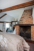 Exposed brick fireplace in bedroom of Sandhurst cottage, Kent, England, UK