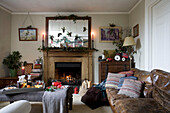Christmas decoration on mirror above lit fire in living room of Tenterden home, Kent, England, UK
