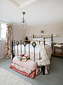 Vintage brass bed with stacked quilts and Christmas stocking in Tenterden home, Kent, England, UK