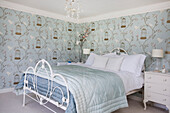Light green and blue quilts on double bed i room with birdcage patterned wallpaper in Tenterden home, Kent, England, UK