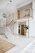 Open plan entrance hall with large pendant shade and metal banisters in modern home Bath Somerset, England, UK