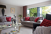 Graue Sofas mit rot gepunkteten Kissen im Wohnzimmer eines modernen Hauses in Bath Somerset, England, UK