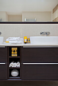 Wash basins with dark wood storage in bathroom of modern home Bath Somerset, England, UK