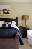 Black quilt on dark wood bed with matching gold lamps in Smarden home Kent England UK