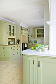 Light green open plan kitchen in Kent home England UK