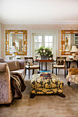 Vergoldeter Spiegel im Wohnzimmer mit gepolstertem Sessel und Hocker in einem Haus in Kent, England, UK