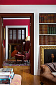 View through doorway from library with hardbacked books and gilt framed oil painting in Kent home England UK