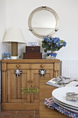 Rope lamp base on wooden sideboard below porthole mirror in Dartmouth home, Devon, UK