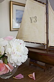 Cut flowers and model boat on sideboard in Dartmouth home, Devon, UK