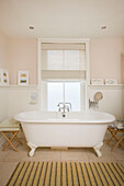 Freestanding white roll-top bath at window of Deal home Kent England UK