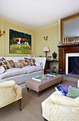 Artwork above sofa with ottoman footstool in living room of Etchingham farmhouse East Sussex England UK