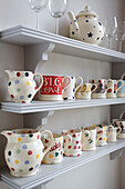 Verschiedene Porzellanteller und Krüge auf Küchenregalen in einem Haus in Kilndown, Cranbrook, Kent, England, UK