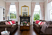 Rosa Kissen auf Sofa mit Holztisch und Schublade im Wohnzimmer von Kilndown home Cranbrook Kent England UK