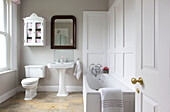 Wall mounted bathroom cabinet with vintage mirror above washbasin in Kilndown home Cranbrook Kent England UK