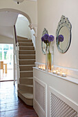 Lit candles on radiator shel with carpeted hallway in Staplehurst home Kent England UK